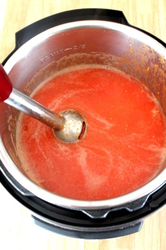 Using immersion blender to puree cooked tomatoes for homemade ketchup
