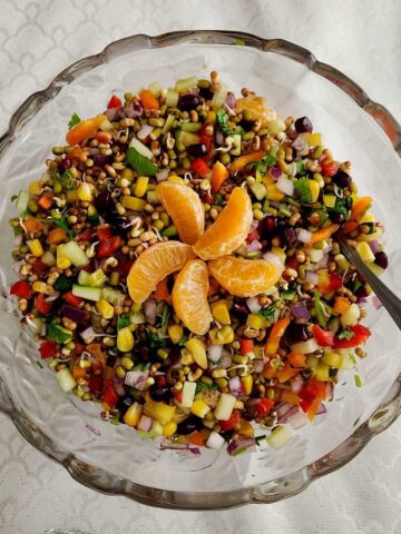 Sprouted mung bean salad with cucumber, tomato, avocado, and chaat masala in a white bowl