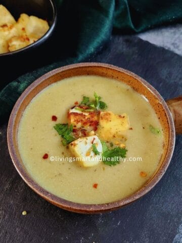Paneer lauki soup in a white bowl garnished with paneer croutons, fresh coriander and cracked black pepper