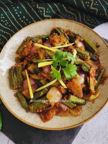 Bhindi Do Pyaza plated on a white dish with a side of phulka roti and sliced green chili garnish, shot from above