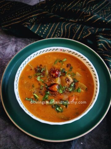 Close up of homemade sambar with drumstick, carrot, and okra in a rich tamarind lentil broth