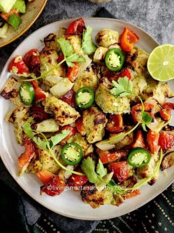 Hariyali chicken tikka kebab served on a platter with sliced onions, lemon wedges, and green chutney