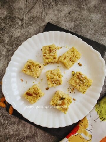 Kalakand squares topped with pistachios and saffron on a plate